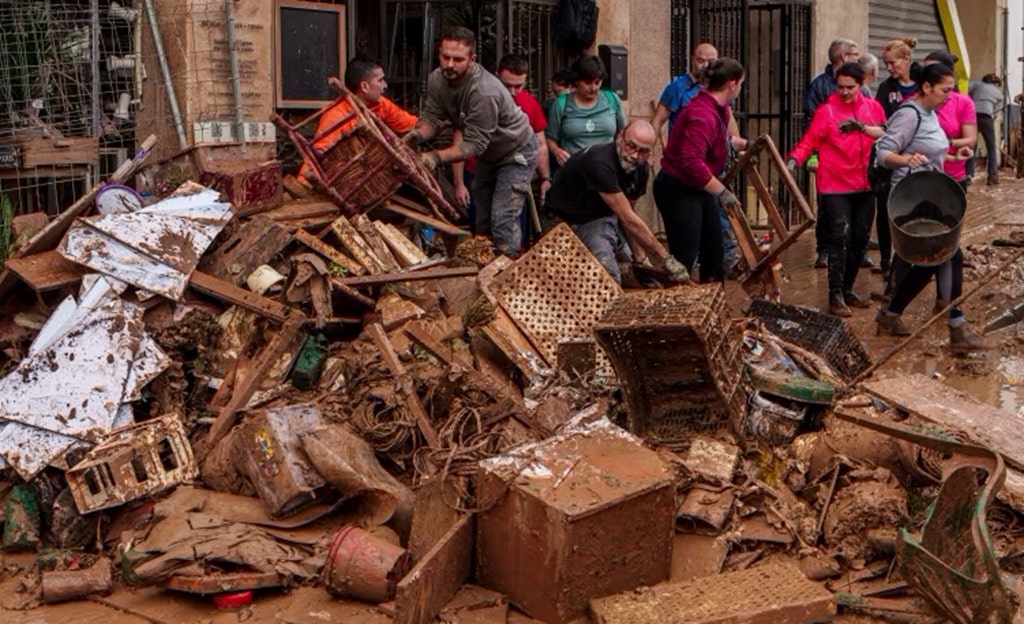 People clean mud from a shop affected by floods in Valencia, Spain.